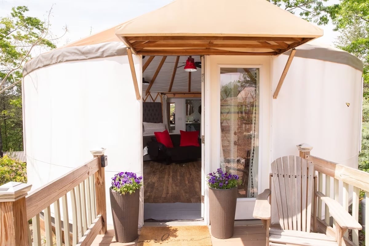 A white yurt with an open door in the woods
